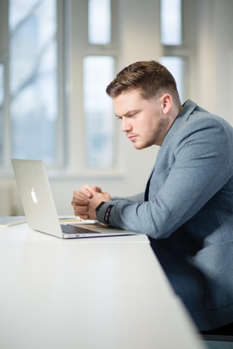 Man sitting on a desk working on a laptop